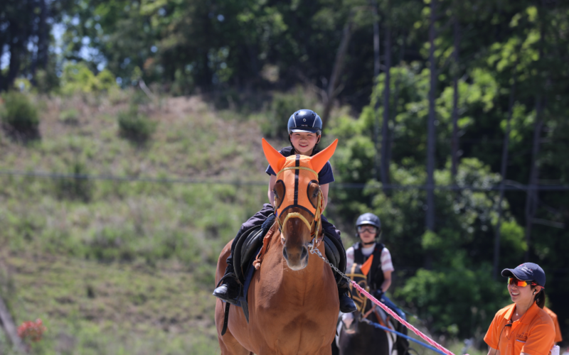 乗馬を楽しむ子どもとサポートスタッフの風景